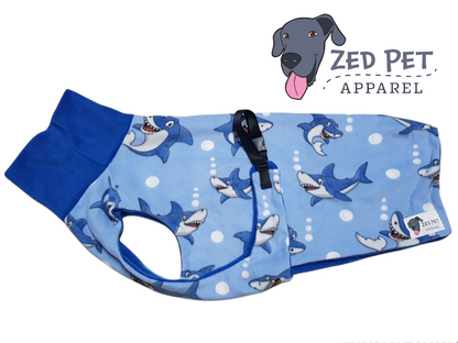Light blue dog coat with dark blue sharks and a dark blue turtleneck on the coat