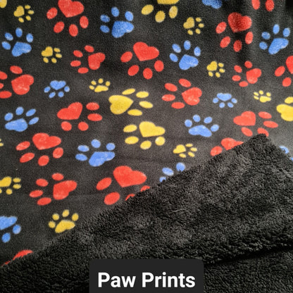 Black polar fleece fabric with red, yellow and blue paw prints