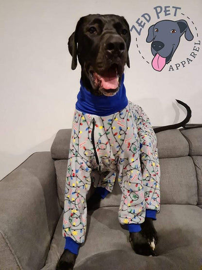 Great dane wearing a onesie printed with christmas lights while sitting on a grey couch